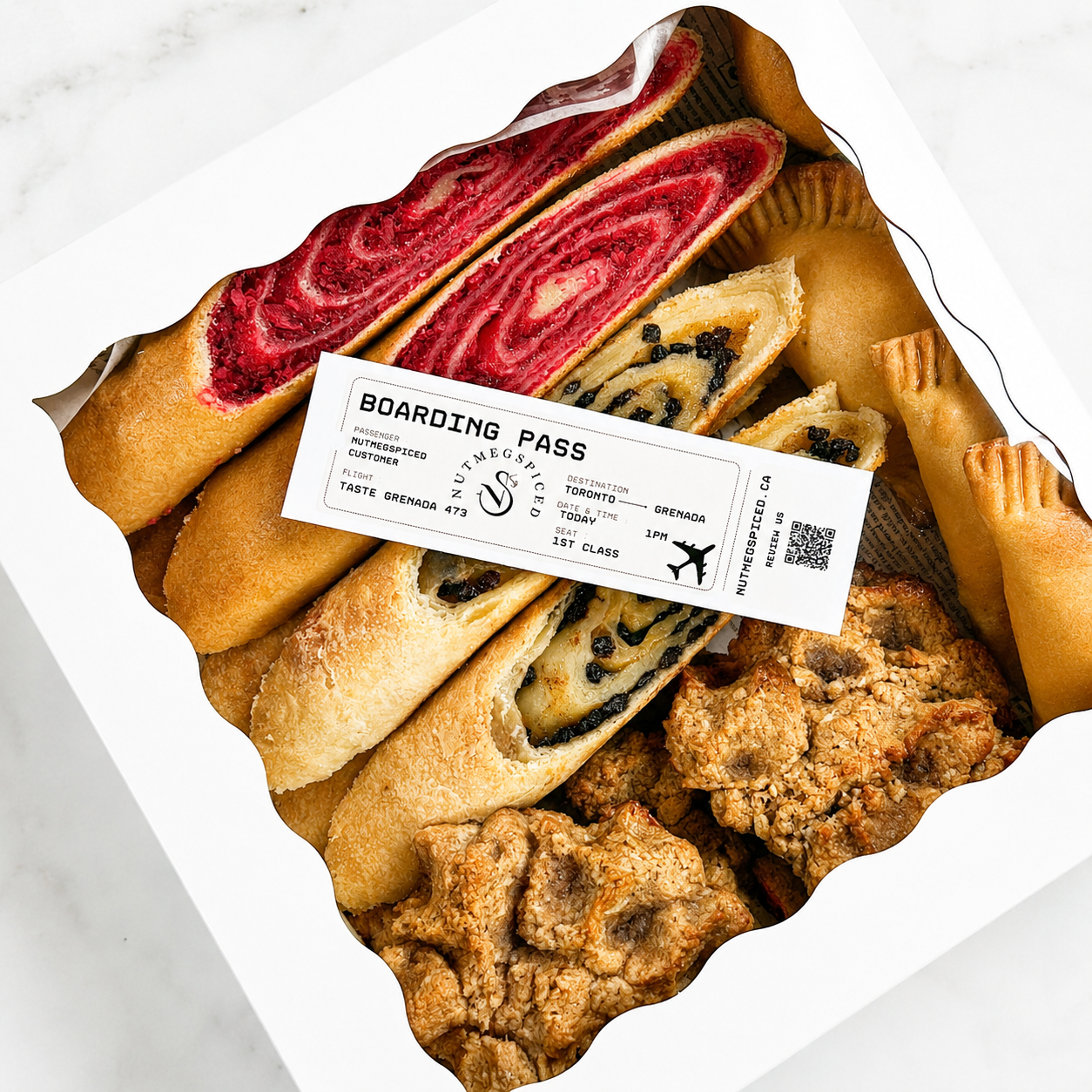 Assorted Grenadian pastries in a box with a boarding pass ticket on top